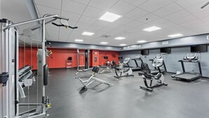 A gym with various exercise equipment, including treadmills, elliptical machines, and weight machines.