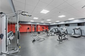 Un gimnasio con equipo de ejercicio variado, incluyendo cintas de correr, elípticas y máquinas de pesas.