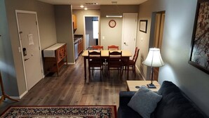 A compact living space with a dining area, kitchenette, and a sofa with a lamp. - Chateau Rose (Branson)