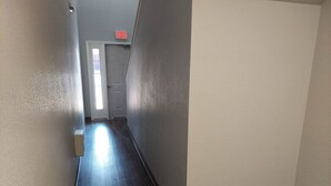 A narrow hallway with a wooden floor, a white door at the end, and an EXIT sign above it. - Chateau Rose (Branson)