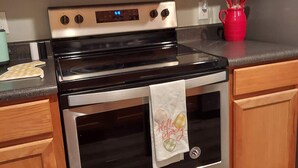 A kitchen with a stainless steel microwave, oven, and a red mug on the counter. - Chateau Rose (Branson)