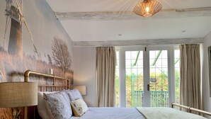 Une chambre à coucher avec un lit, une table de chevet, une lampe et une vue sur l’extérieur par une fenêtre.