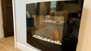 Un salon moderne avec un grand téléviseur à écran incurvé, une petite table et un canapé.