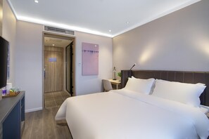 Habitació d'hotel amb un llit, escriptori, cadira, televisió i una porta que condueix a una altra habitació.