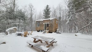 Una pequeña cabaña de madera rodeada de árboles cubiertos de nieve.