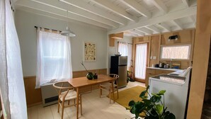 A compact kitchen with a dining area, wooden cabinets, a refrigerator, and a sink. - Modern Cottage 1 (The Lorca, Catskills) - 10 min to Belleayre, 25 min to Windham (Shandaken)