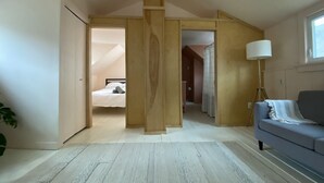 A modern, open-plan living space with a loft bedroom, a sofa, and a floor lamp. - Modern Cottage 1 (The Lorca, Catskills) - 10 min to Belleayre, 25 min to Windham (Shandaken)