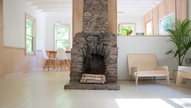A spacious room with a stone fireplace, wooden flooring, and large windows allowing natural light. - Modern Cottage 1 (The Lorca, Catskills) - 10 min to Belleayre, 25 min to Windham (Shandaken)