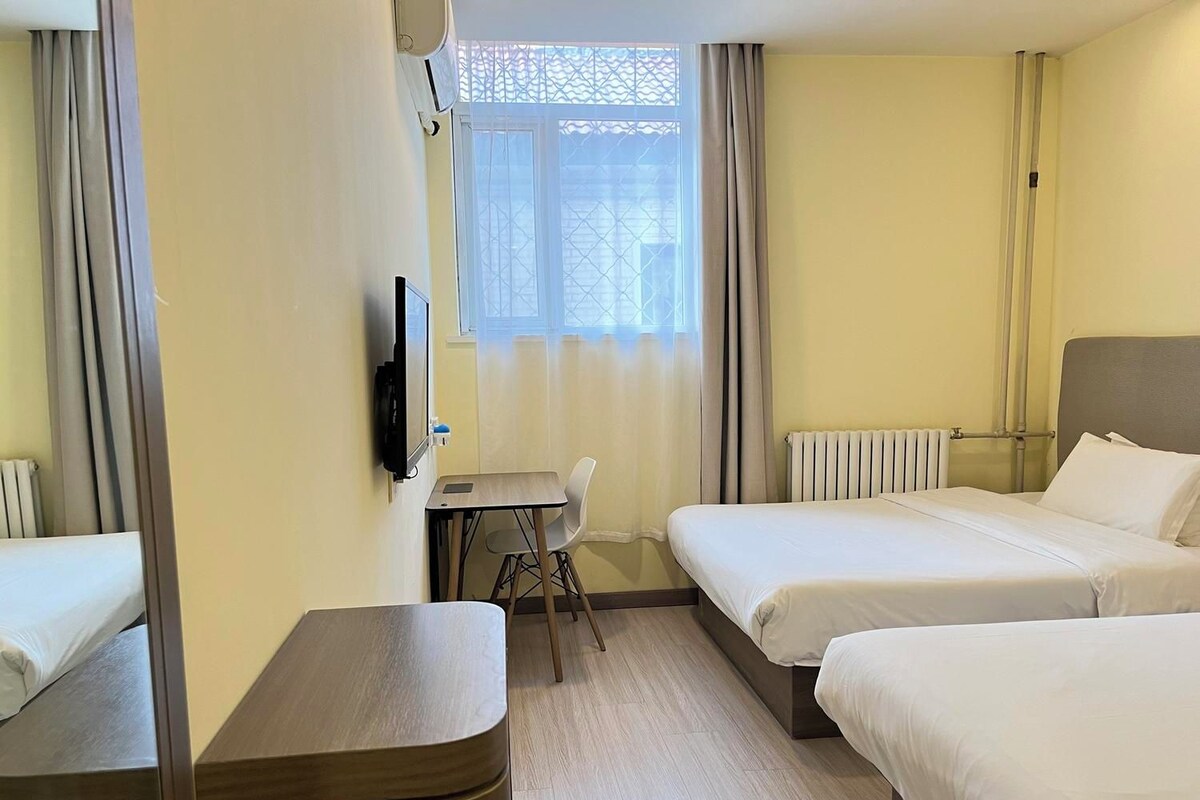 Ein Hotelzimmer mit Bett, Schreibtisch, Stuhl und Fernseher.