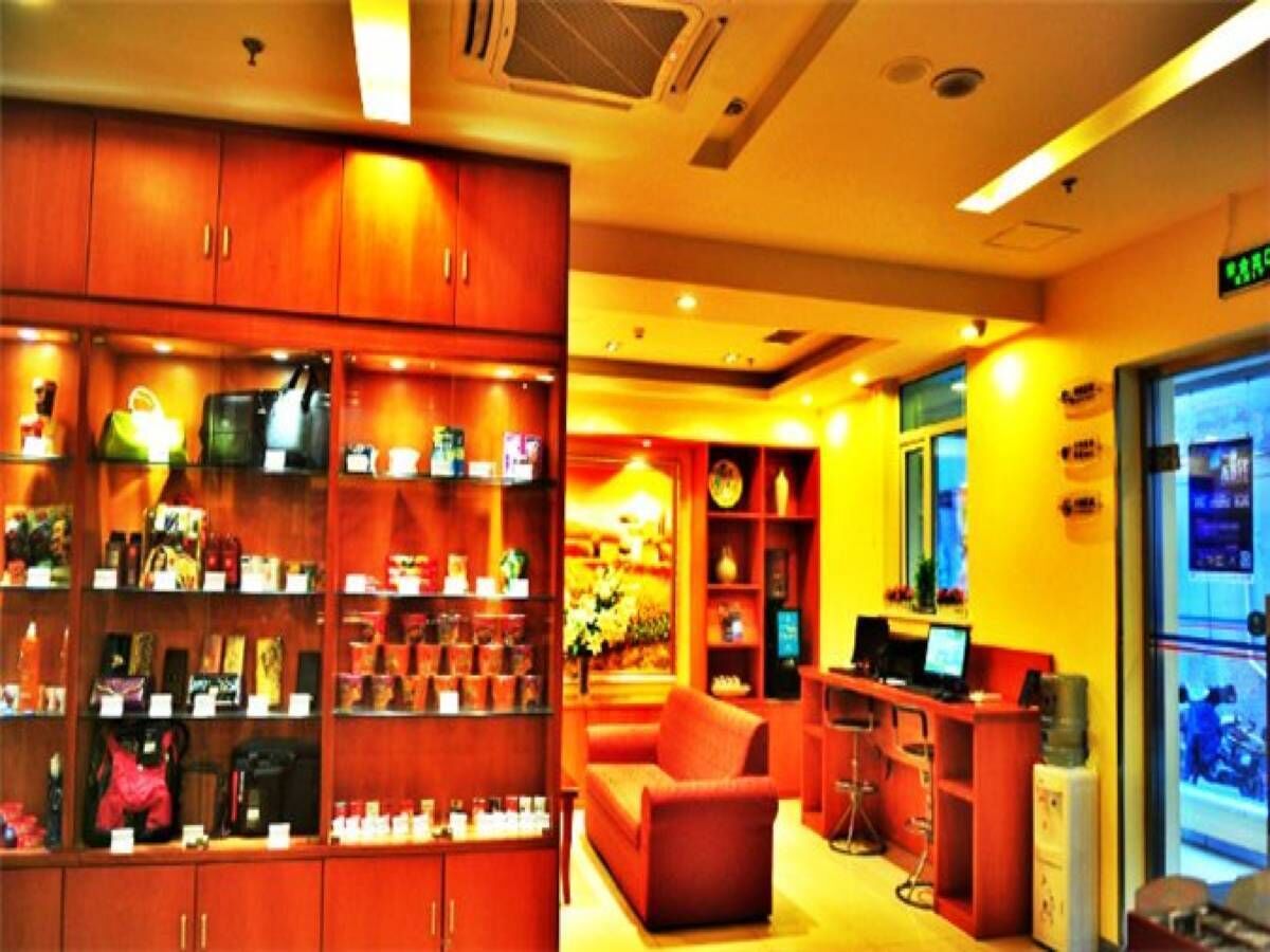 A hotel lobby with wooden cabinets, a sofa, a desk with a computer, and a glass door leading outside.