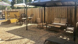 A covered patio area with outdoor furniture, including a sofa and chairs, under a pergola. - Big Green House 4bdrm - 3 bath with Pool Table (Templeton)