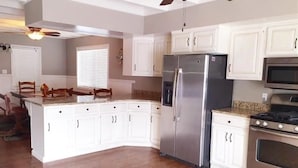 A kitchen with white cabinets, a stainless steel refrigerator, a microwave, and an oven. - Big Green House 4bdrm - 3 bath with Pool Table (Templeton)