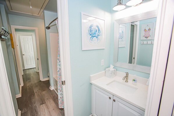 Une salle de bain avec un meuble-lavabo blanc, un grand miroir et un rideau de douche.