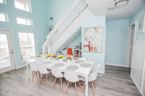 A dining area with a white table, white chairs, and a staircase. - Dog Friendly Beach House, Steps to Beach, Ocean View Sleeps 10! (Freeport)