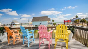 Una terraza de madera con sillas Adirondack de colores que dan al mar.