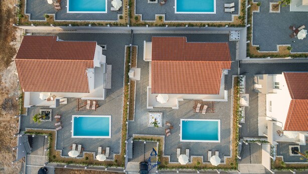 An aerial view of a resort with multiple pools, each surrounded by lounge chairs and umbrellas, and buildings with red-tiled roofs. - Modern 4 BD villa with heated pool for up to 8 guests (Sukošan)