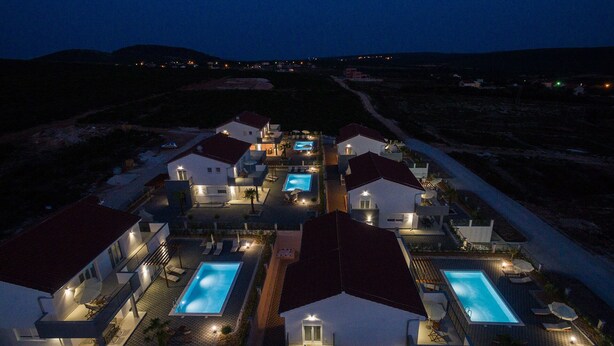 Un resort con diverse piscine, ognuna circondata da lettini e ombrelloni, e collegate da vialetti.