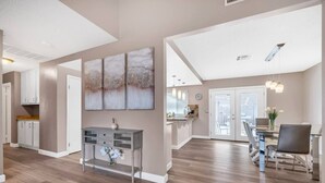 A spacious living area with a dining table and chairs, a kitchen with white cabinets, and a hallway with a door. - Perfect Las Vegas Private Retreat w/ Pool & Spa! (Las Vegas)