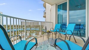 A balcony with blue chairs and a table, overlooking a pool and buildings. - 2705 Gulf Views ~ Super Deal ~ Heated Pool ~ Resort Bar, Hot Tub ~ Book Sept 7th (Destin)