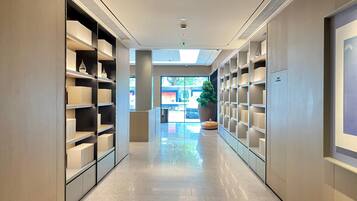 A modern hotel corridor with built-in shelving, a large potted plant, and a view of the outside.