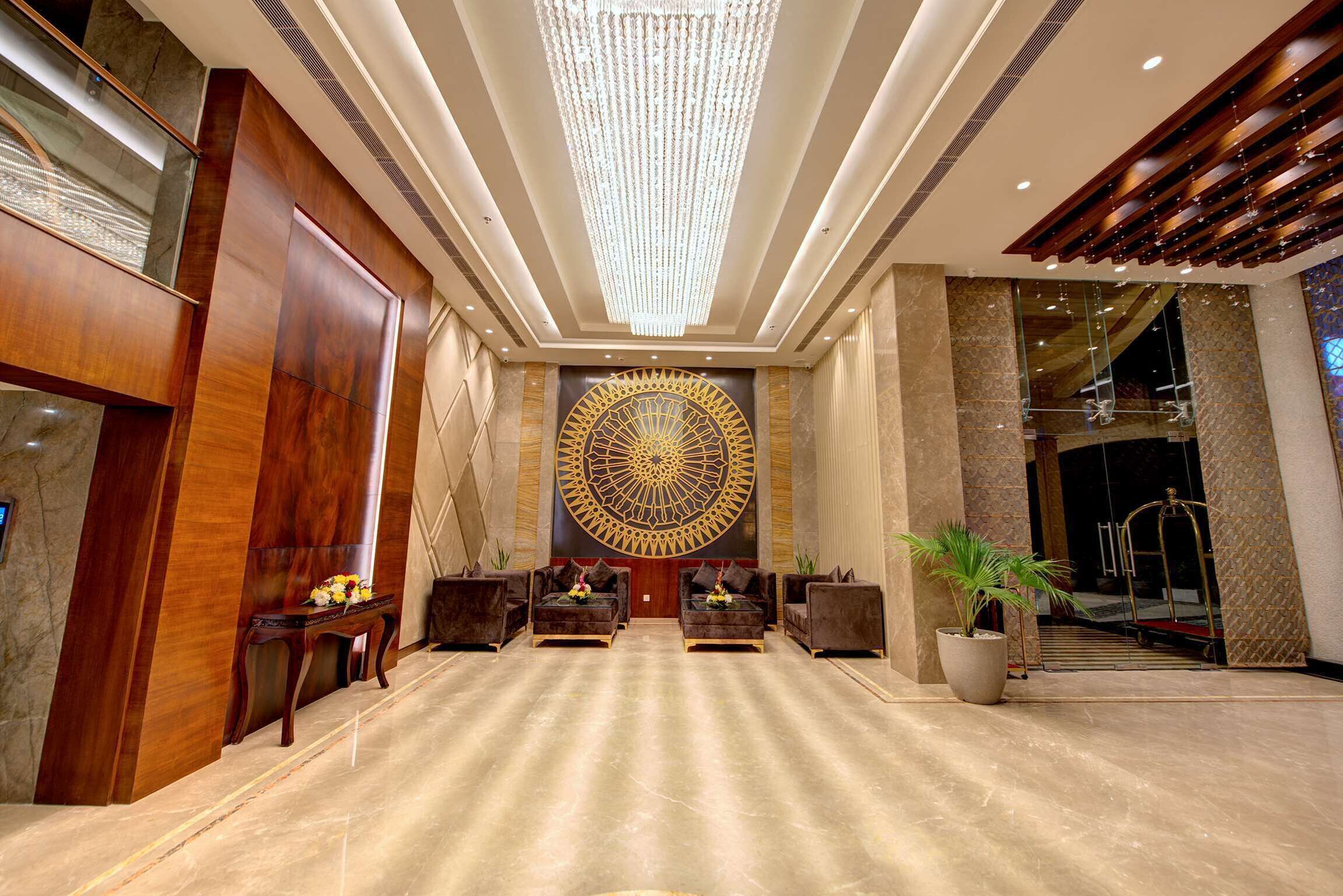 A spacious lobby with a grand chandelier, a large decorative wall piece, and a reception desk.