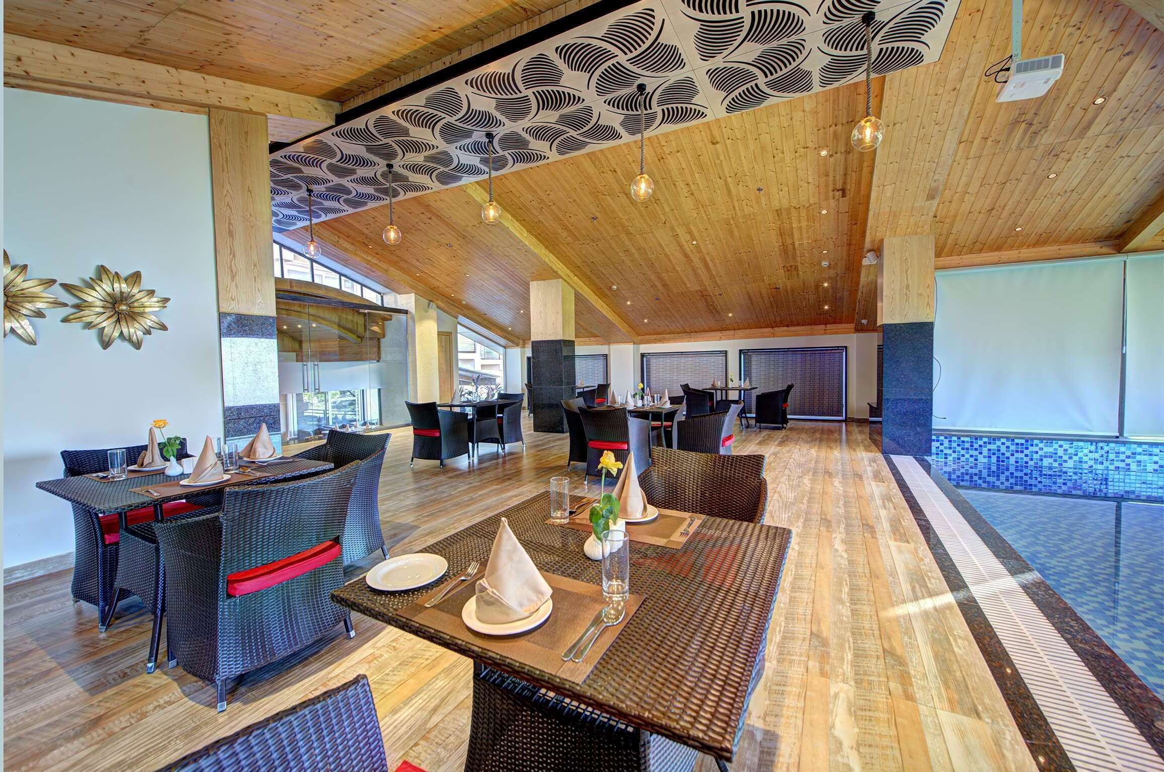 A spacious dining area with high ceilings and modern decor, featuring wicker furniture and a central table set for a meal.