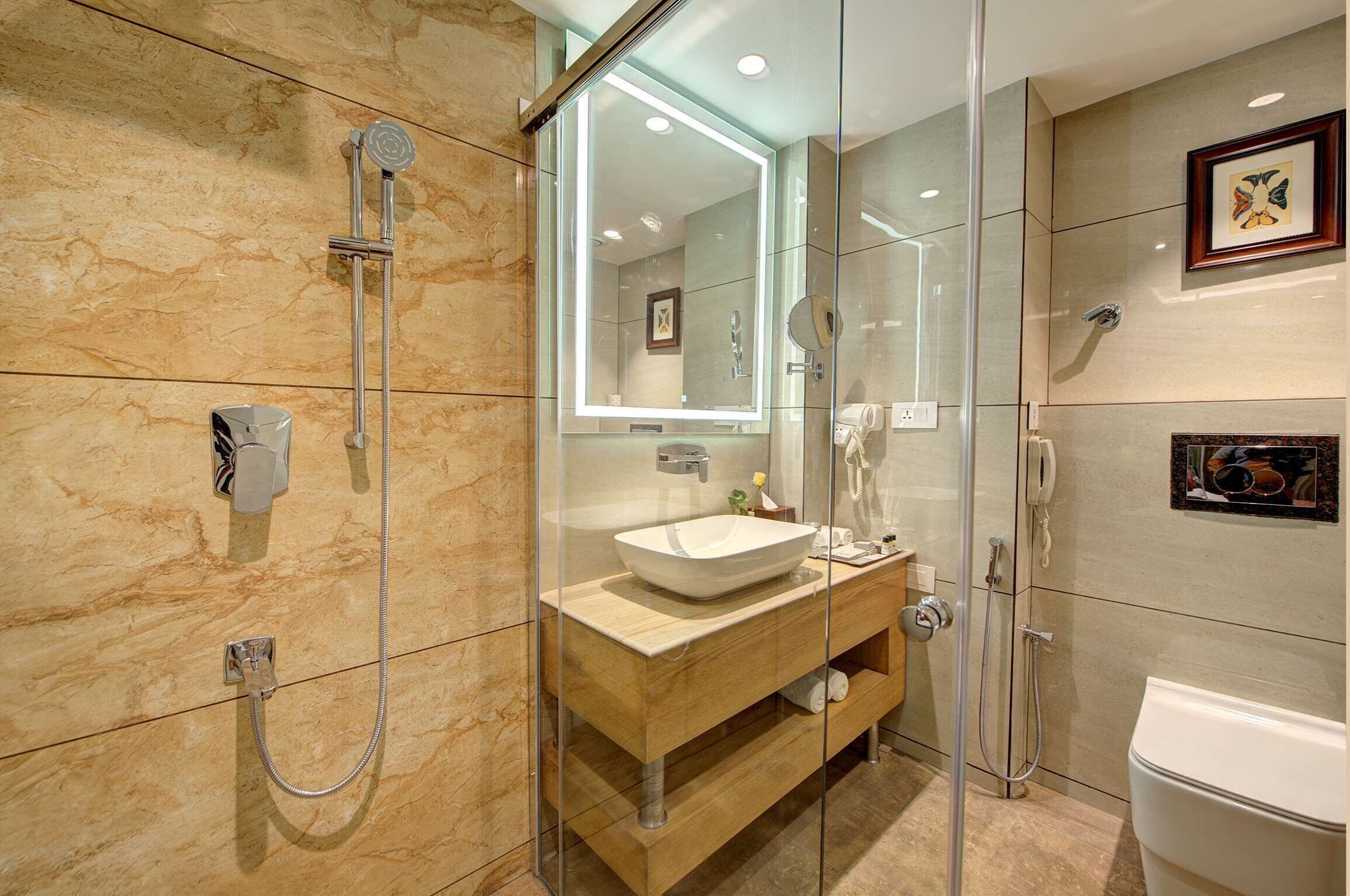 Een moderne badkamer met een glazen douchecabine, een houten wastafelmeubel met een waskom en een toilet.