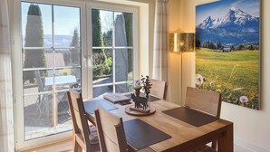 Ein Essbereich mit Tisch, Stühlen und Blick auf eine Berglandschaft durch große Fenster.