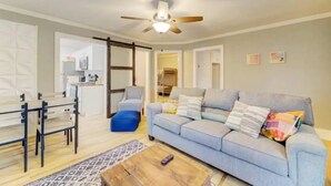 Un salon avec un canapé, une table basse et un ventilateur de plafond.