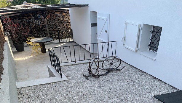 A patio area with a table and chairs, a blue table, and a gravel floor. - Quiet apartment with beautiful terrace (Peyroules)