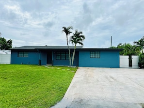 A single-story building with a flat roof, a front lawn, and a gated driveway.