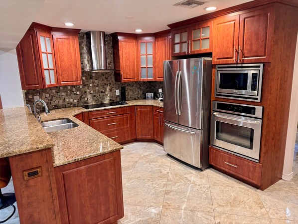 A modern kitchen with wooden cabinets, stainless steel appliances, and a granite countertop.