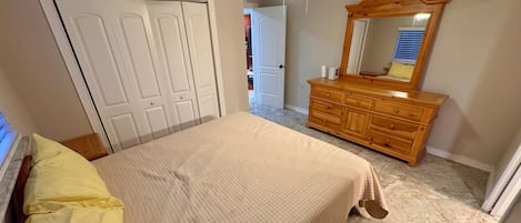 A bedroom with a bed, a dresser, a mirror, and a ceiling fan.