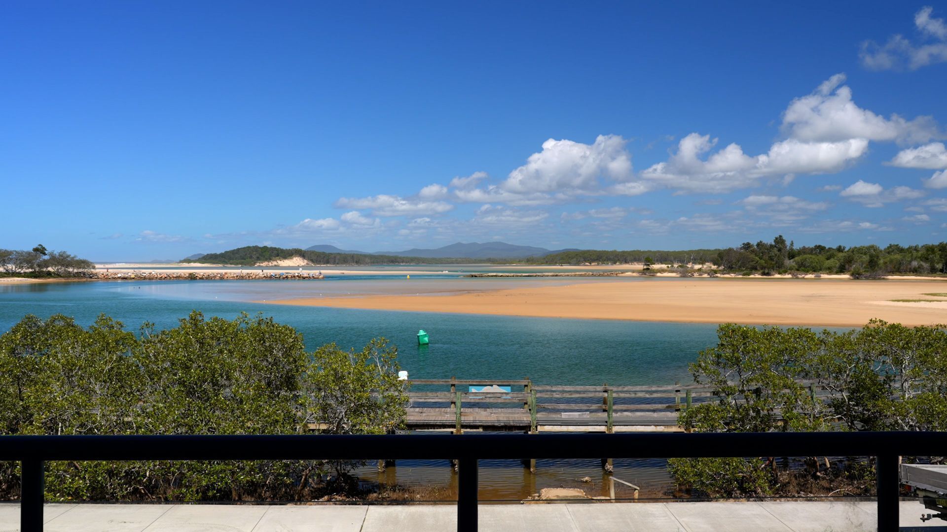 A coastal landscape with a clear sky, a sandy beach, and a calm body of water.