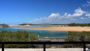 Un paisaje costero con cielo despejado, una playa arenosa y una masa de agua tranquila.