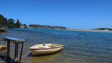 A small boat tied to a dock with clear water and a distant shoreline.