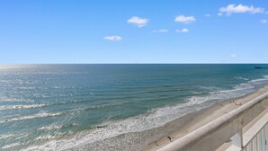 Ein Strand mit blauem Himmel, Wellen und einem Pier in der Ferne.
