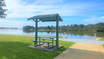 A picnic area with a shelter and benches by a lake.