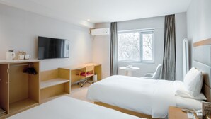 A hotel room with a bed, a desk, a chair, a TV, and a window with curtains. - Ji Hotel (Beijing)