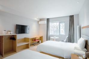 A hotel room with a bed, a desk, a chair, a TV, and a window with curtains. - Ji Hotel (Beijing)