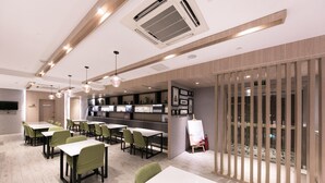 A modern dining area with tables and chairs, a kitchen in the background, and a view through a wooden partition.
