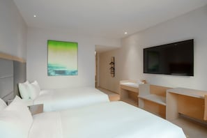 A modern hotel room with two beds, a large TV, a painting, and a small bathroom area. - Ji Hotel (Beijing)