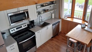 A compact kitchen with a microwave, stove, sink, and coffee maker.