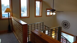 A staircase with wooden railings, a ceiling fan, and three windows with wooden frames.