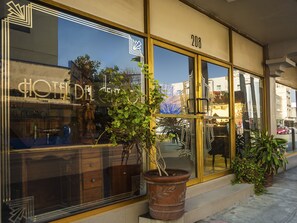 A hotel with large windows, a number 208 sign, and potted plants outside.