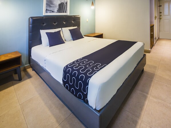 A neatly made bed with a patterned throw, a headboard, and two bedside tables.