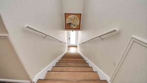 A staircase with white walls and a framed artwork at the top.