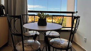 A balcony with a table and chairs, a potted plant, and a view of the ocean.