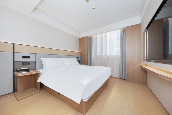 Une chambre d’hôtel moderne avec un grand lit, un bureau et une grande fenêtre.
