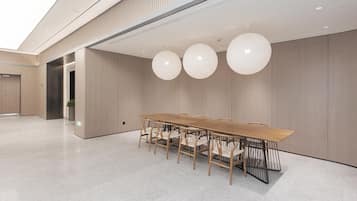A modern conference room with a long wooden table and chairs, large spherical pendant lights, and a minimalist design.